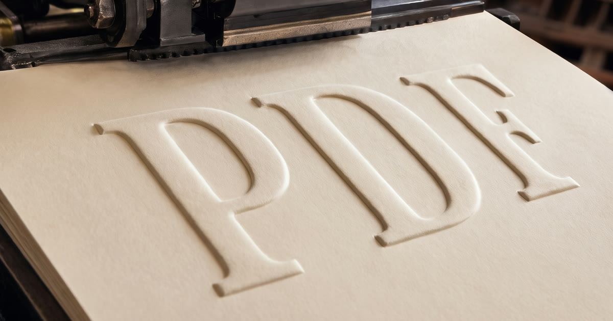 A vintage letterpress with the word PDF blind-embossed into thick cream paper